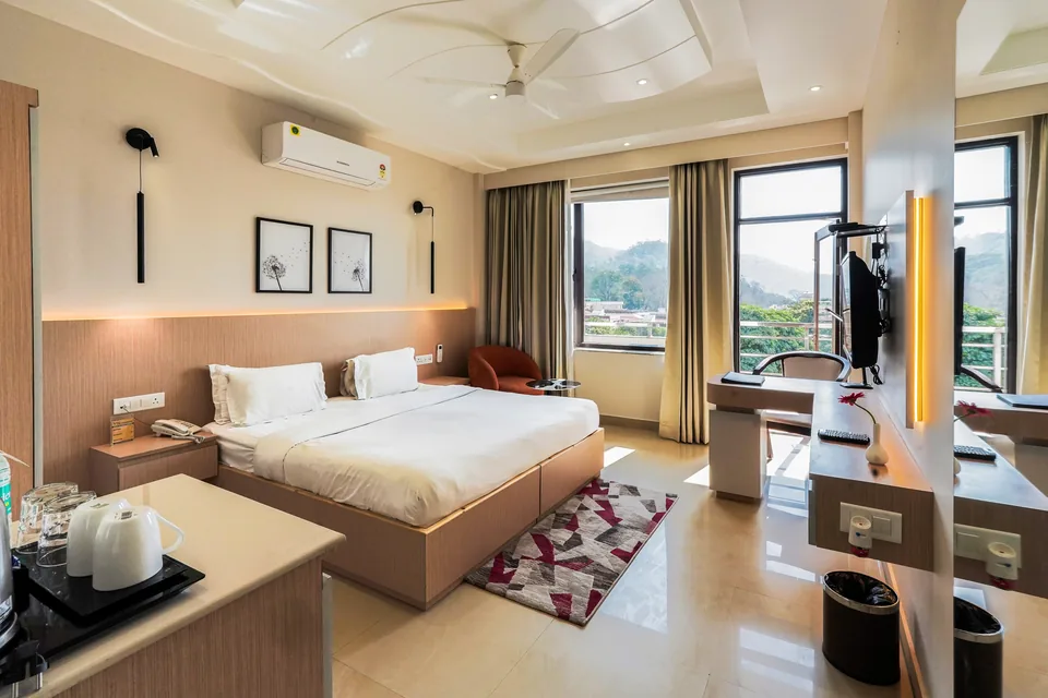 Premiere Room at Hotel Yog Vashishth in Rishikesh with a double bed, workspace and windows overlooking the foothills