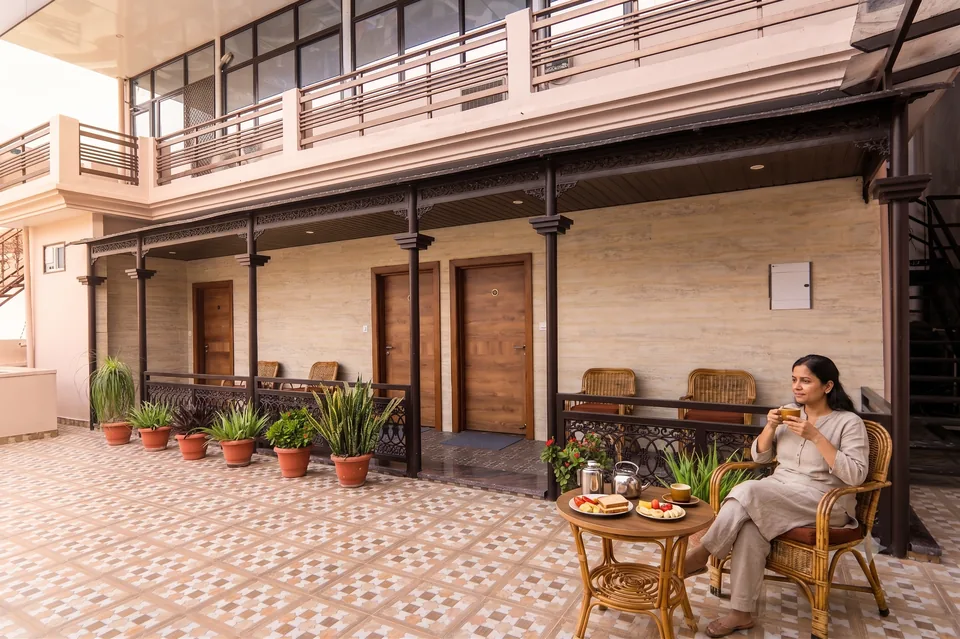 Guest enjoying morning coffee on the plant-filled terrace at Vashishth Guest House in Rishikesh